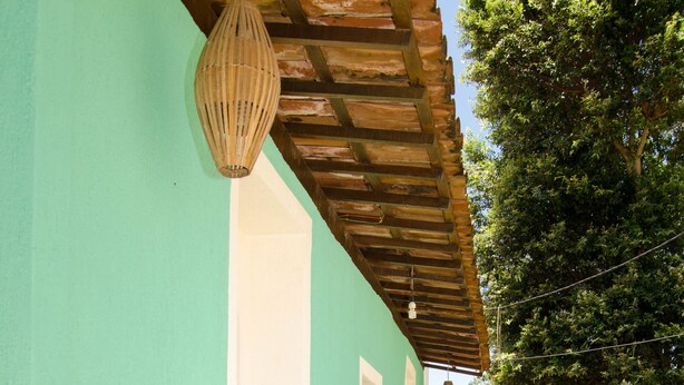 A row of wooden benches under a wooden pergola, with a hanging light fixture above.