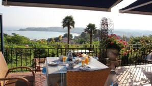 Una terraza con una mesa dispuesta para el desayuno, con vistas a un paisaje costero.