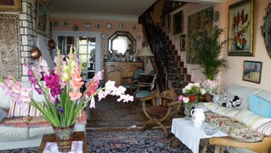 Un salón tradicional con una alfombra estampada, un sofá, una silla de madera y una mesa con un jarrón de flores.