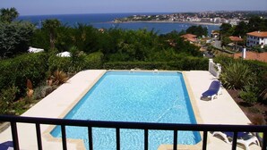 A rectangular swimming pool with clear blue water, surrounded by a white deck and a black railing. - Villa Erresinolettean (Ciboure)