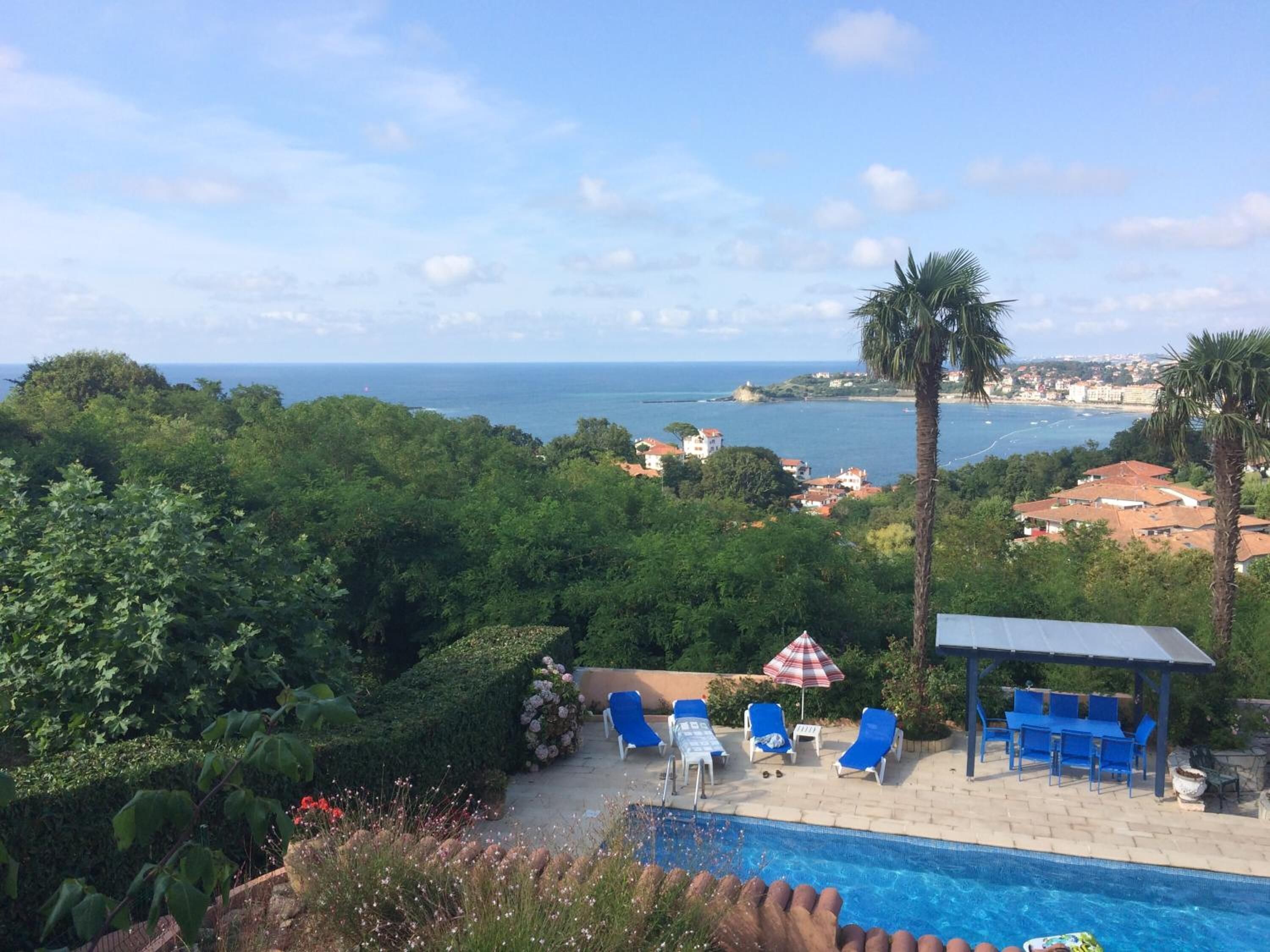 Zona de piscina con sillones de descanso y vistas al mar.