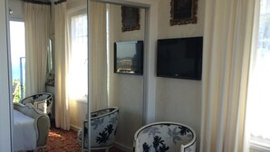 Un dormitorio con cama, una silla, un televisor y un espejo.