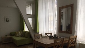 A cozy living space with a wooden dining table, green sofa, and a large mirror.