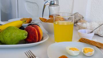 A breakfast setting with fruits, eggs, toast, and a glass of juice on a table.