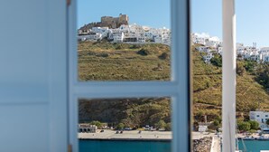 A coastal town with white buildings, a prominent hilltop structure, and a marina with boats. - Ihthioessa Boutique Hotel (Astypalaia)