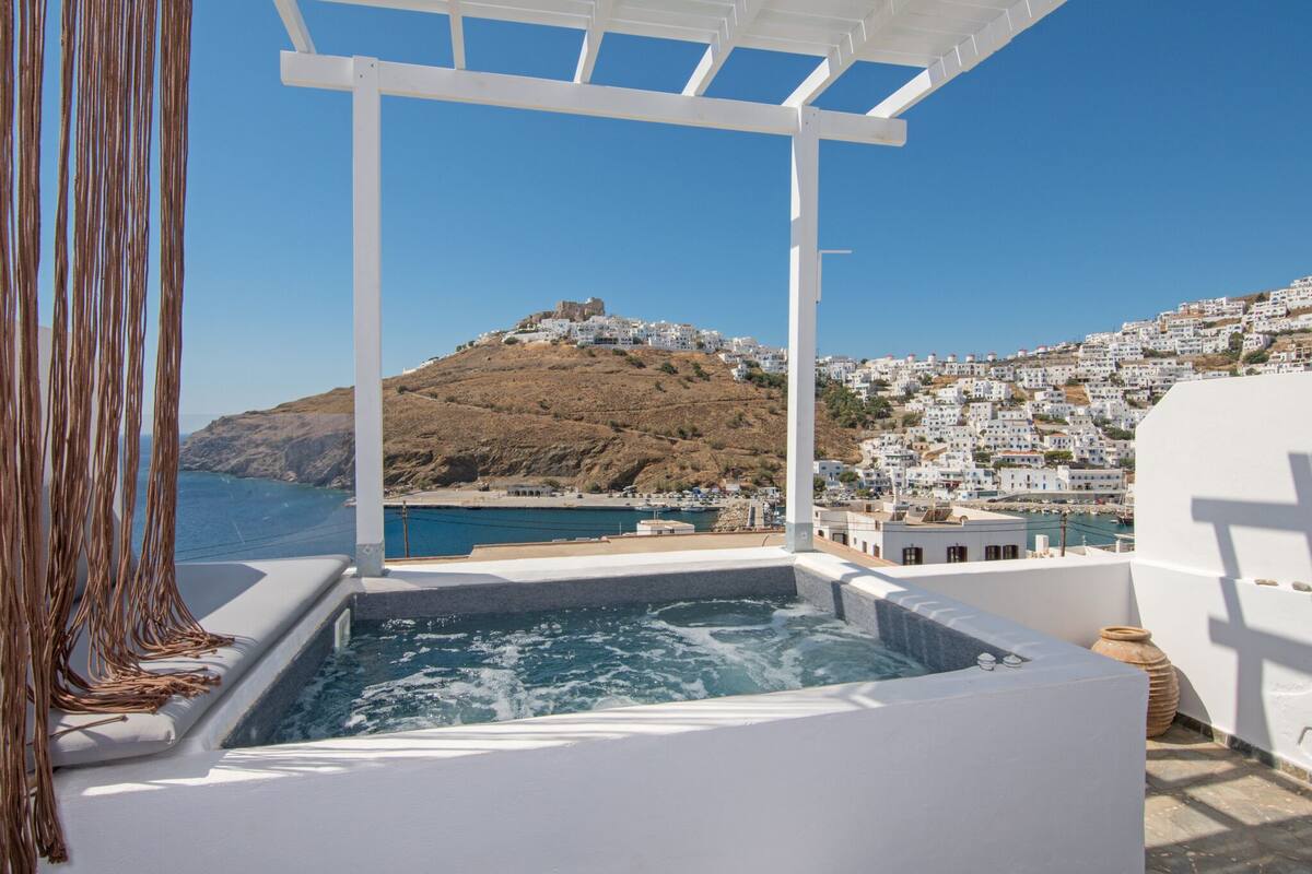 Un bain à remous avec vue sur une ville côtière et une colline parsemée de bâtiments.