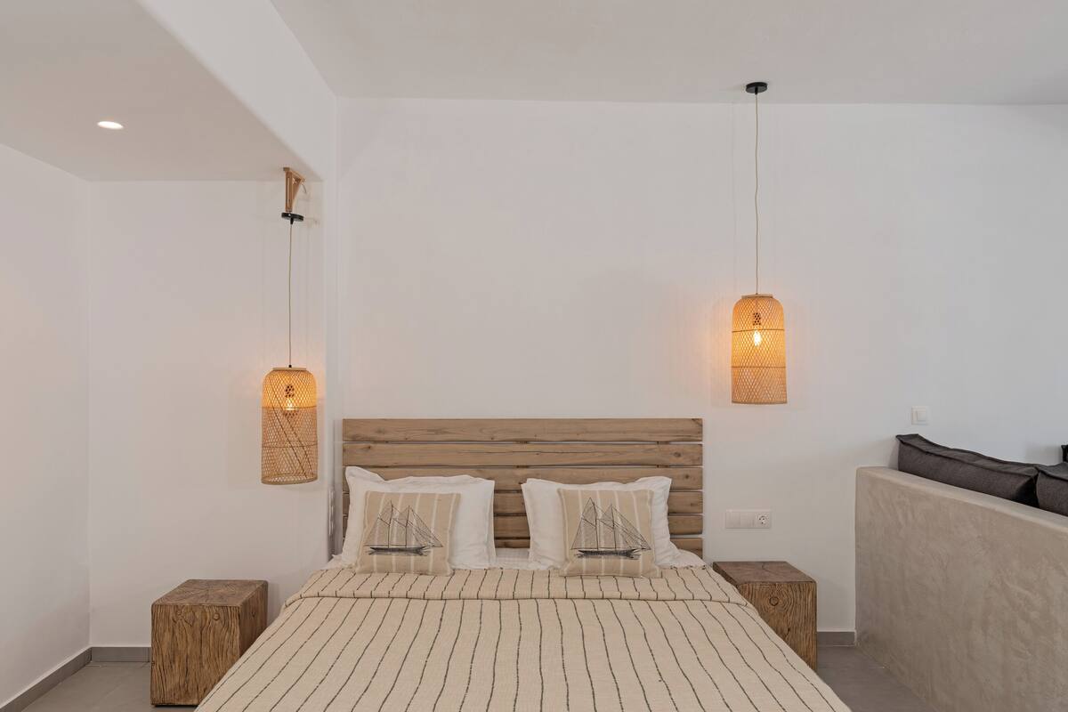Une chambre à coucher moderne avec une tête de lit en bois, deux tables de chevet et un grand lit avec une literie à rayures.