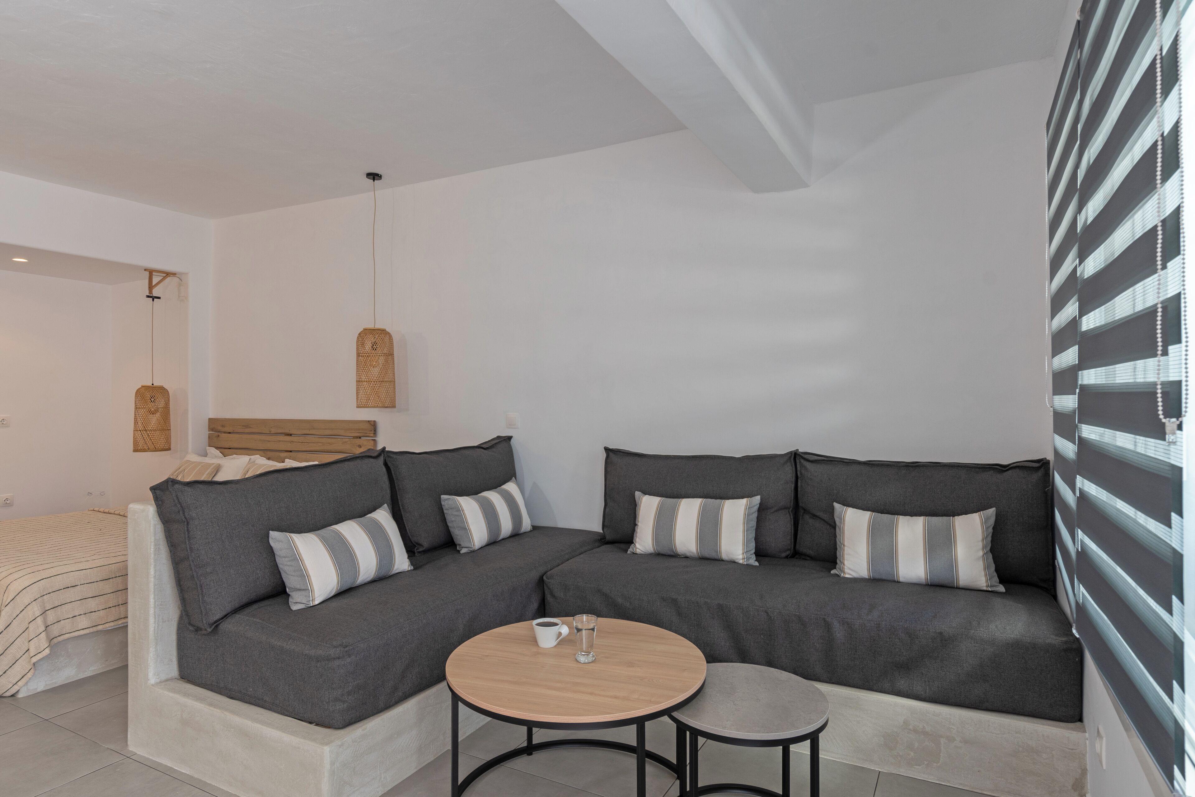 A modern living room with a sectional sofa, a small round table, and a bed in the background.