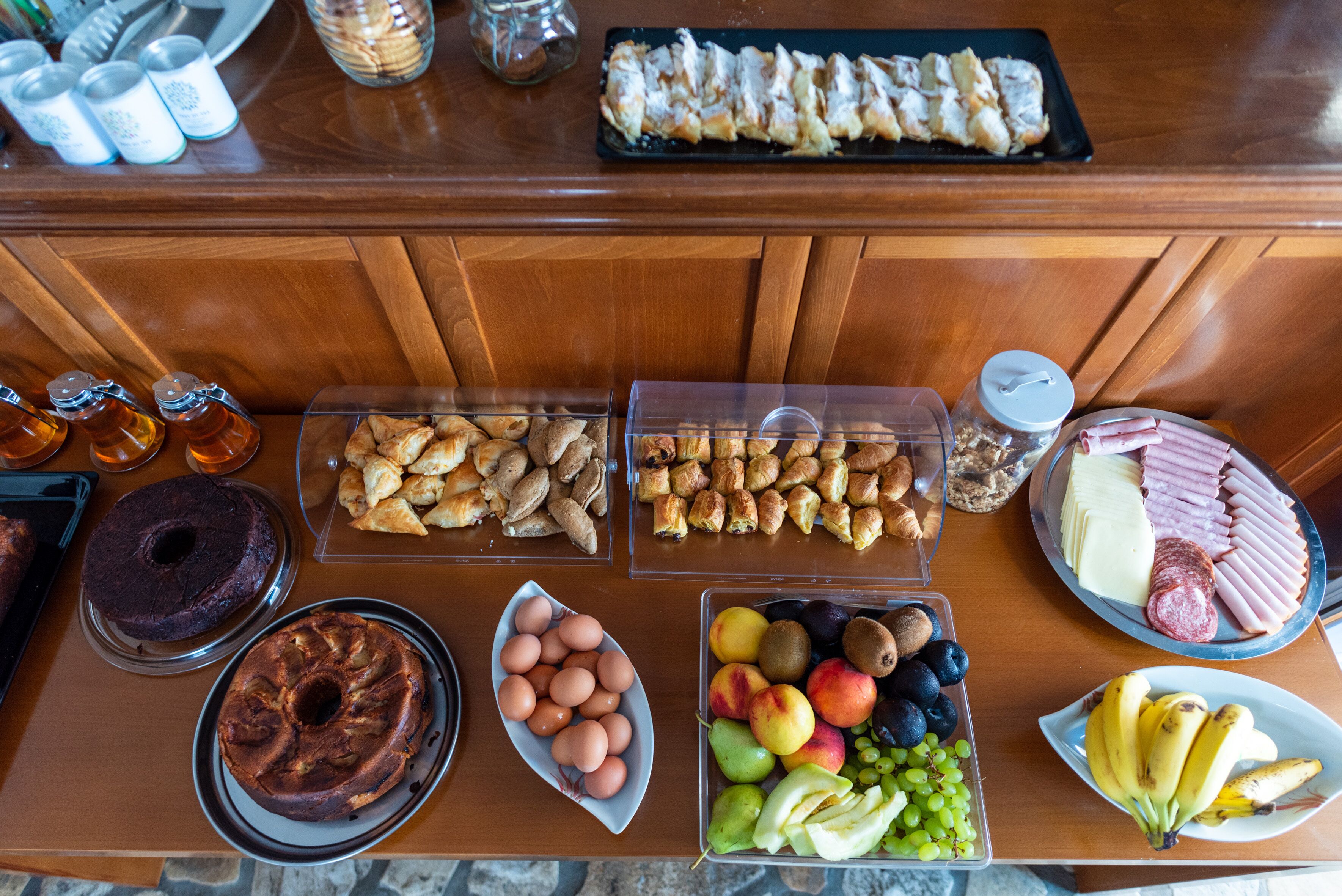 A buffet with various food items including pastries, fruits, and meats.