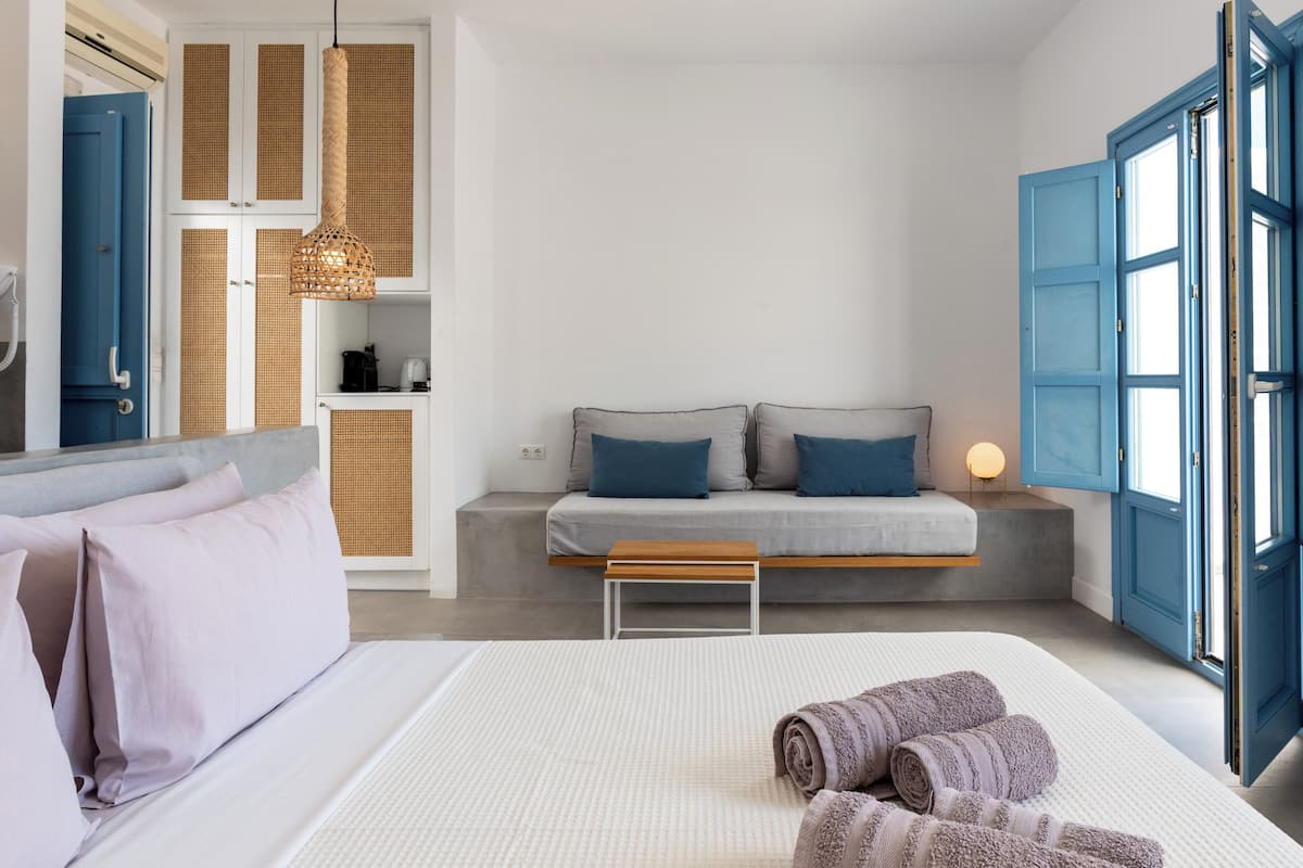 Une chambre moderne avec un grand lit, un banc, un canapé et un luminaire suspendu.