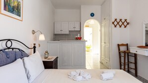 Un dormitorio con cama, mesita de noche, lámpara y baño visible a través de una puerta abierta.