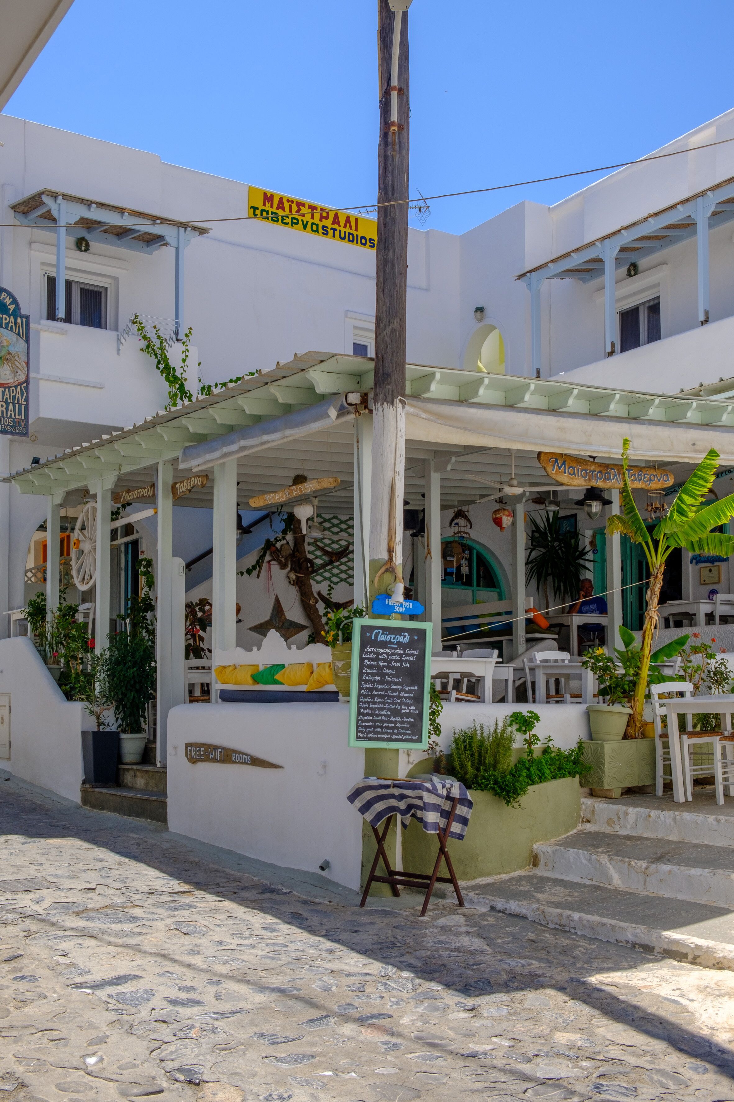 Un edificio blanco con un área de estar al aire libre cubierta, un letrero que dice 'MATZPAI TRESPOVA STUDIO' y un cartel de 'FREE WIFI'.