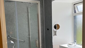 A modern bathroom with a glass-enclosed shower, a white sink, and a mirror with a round frame. - Kilmartin Hotel (Lochgilphead)