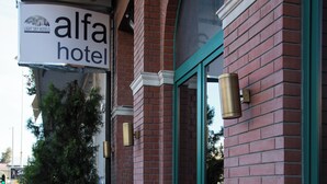 Hotellin kyltti, jossa lukee ”Alfa Hotel”, ja jossa on tiiliverhous sekä vihreät ikkunakehykset.