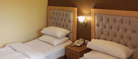 A hotel room with two beds, a bedside telephone, and wall-mounted air conditioning.
