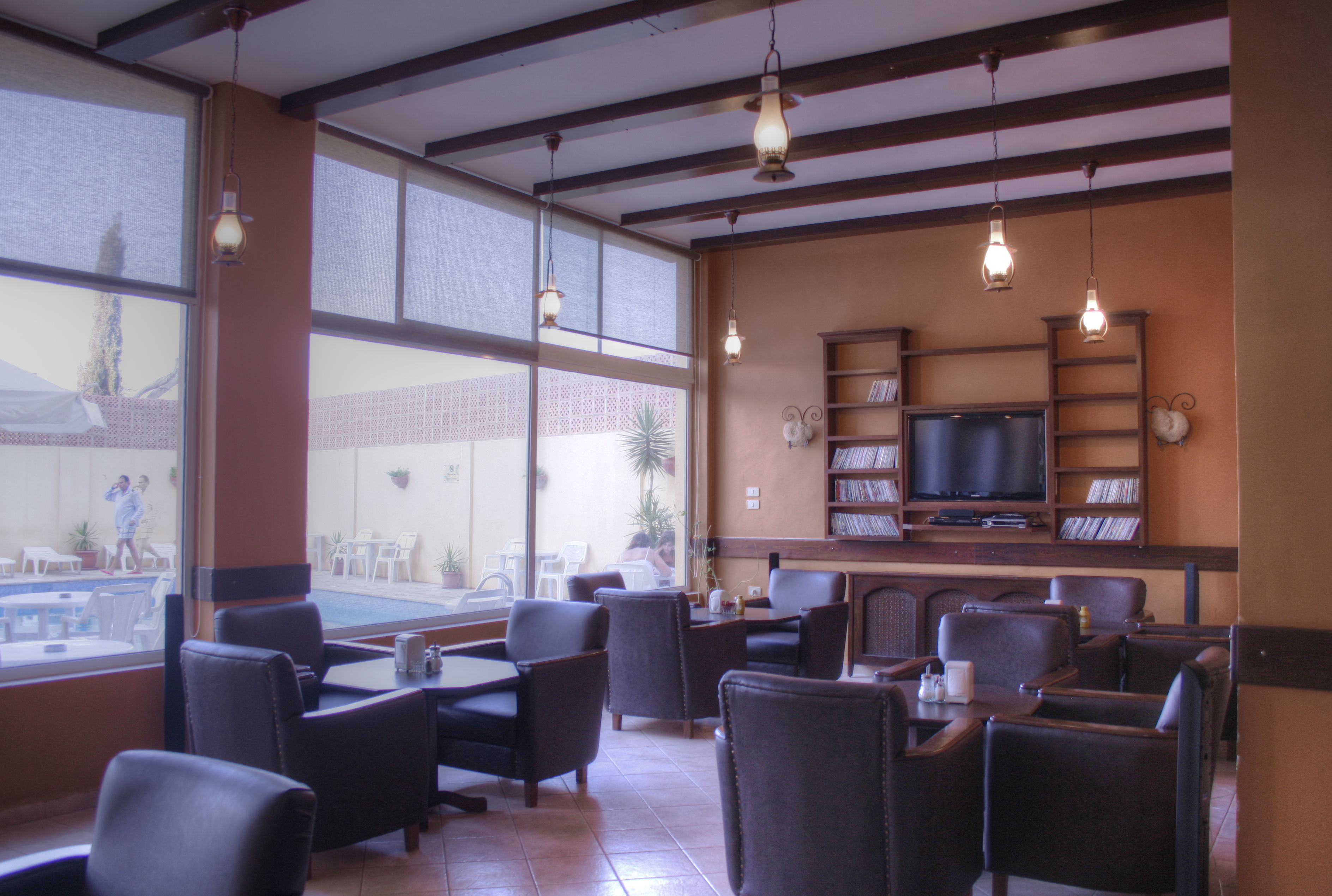 Ein Restaurant mit Blick auf einen Pool, Ledersessel, einem Fernseher und einem Bücherregal.