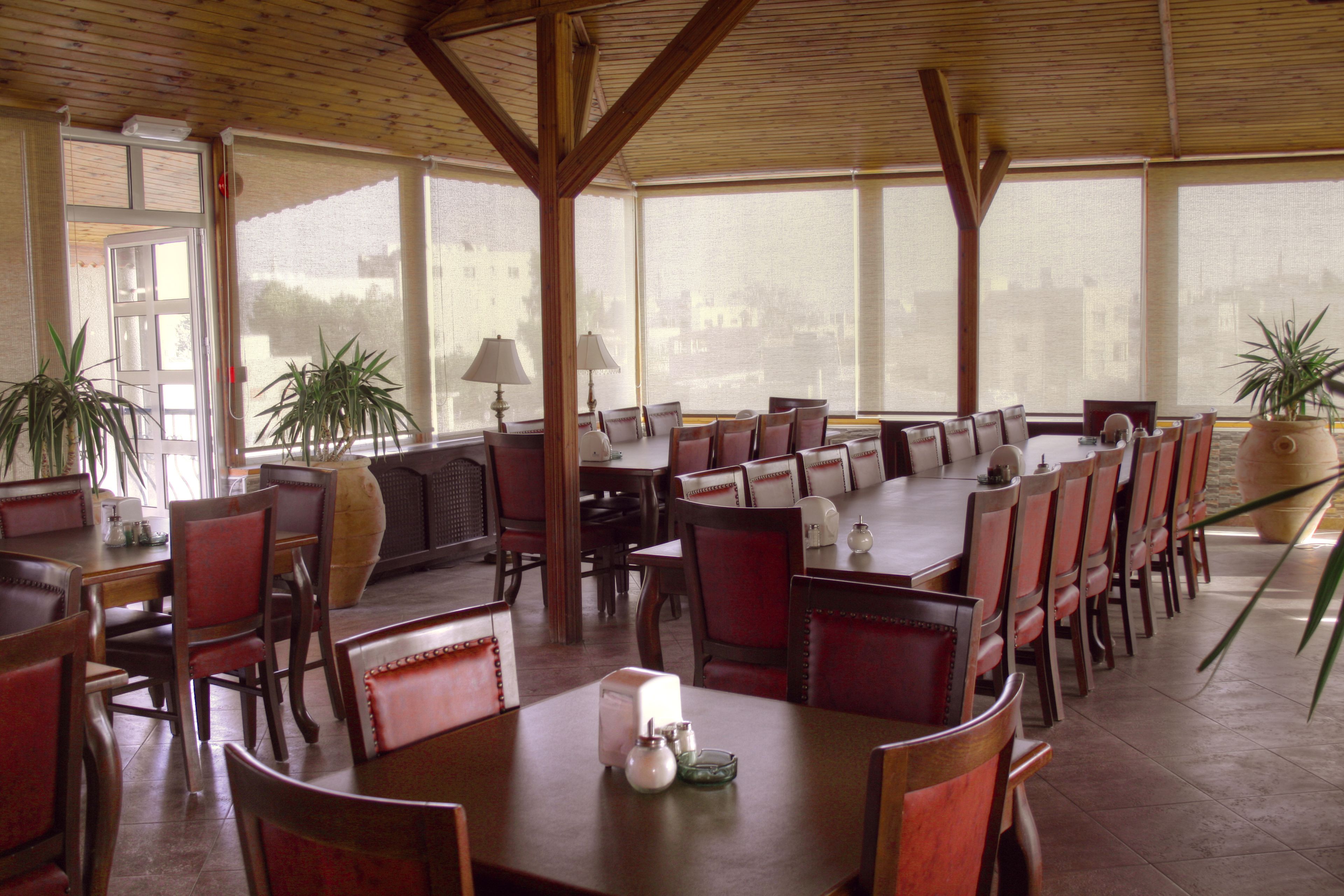 Un vaste espace dédié à la salle à manger, doté de hauts plafonds et de grandes fenêtres, et comprenant plusieurs tables et chaises.