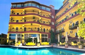 A multi-story hotel with balconies, a swimming pool, and outdoor seating.