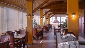 Un restaurante con vigas de madera, pilares amarillos y una larga barra con platos y cuencos.