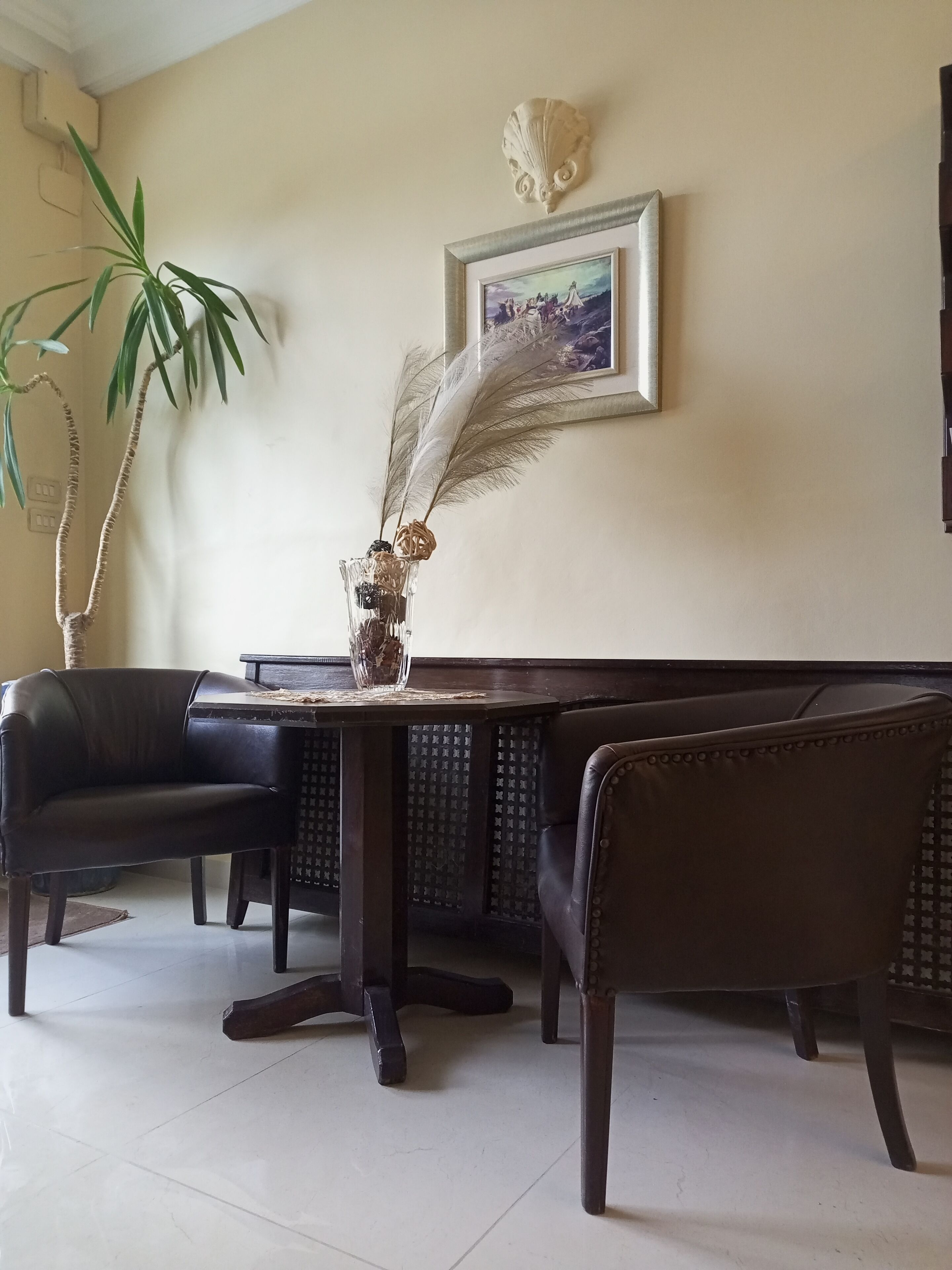 A dining area with a table, chairs, and a decorative vase with dried plants.