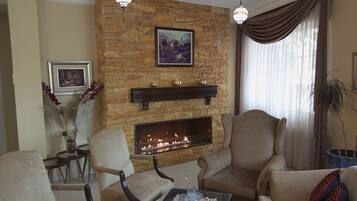 Una sala de estar con chimenea de piedra, dos sillones, una mesa de centro y una araña.