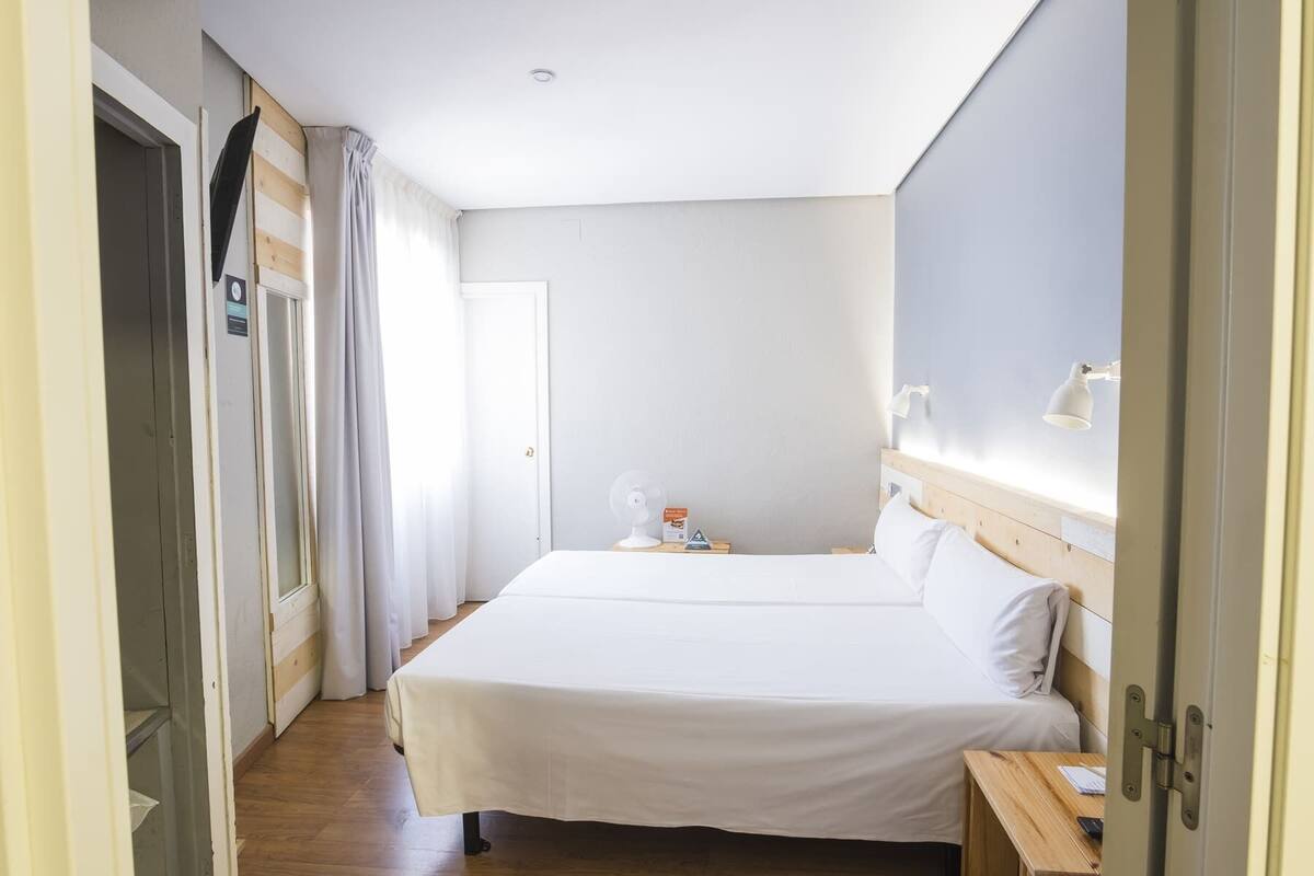 Ein Hotelzimmer mit Doppelbett, Nachttisch und einem kleinen Schreibtisch mit Lampe.