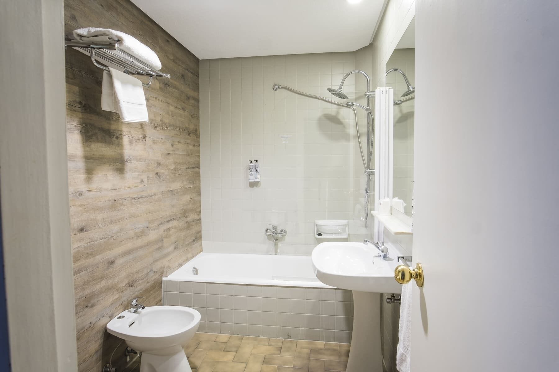 A modern bathroom with a wooden wall, a bathtub, a sink, and a shower.