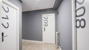 A hallway with grey walls, a white door labeled '209', and a radiator on the right.