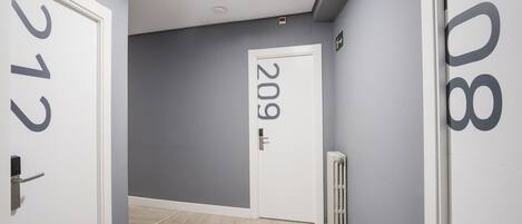 A hallway with grey walls, a white door labeled '209', and a radiator on the right.