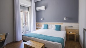 Una habitación de hotel con cama, mesitas de noche, escritorio y ventana con cortinas.