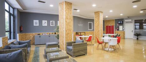 A modern lobby with wicker furniture, a kitchen area, and a dining space.