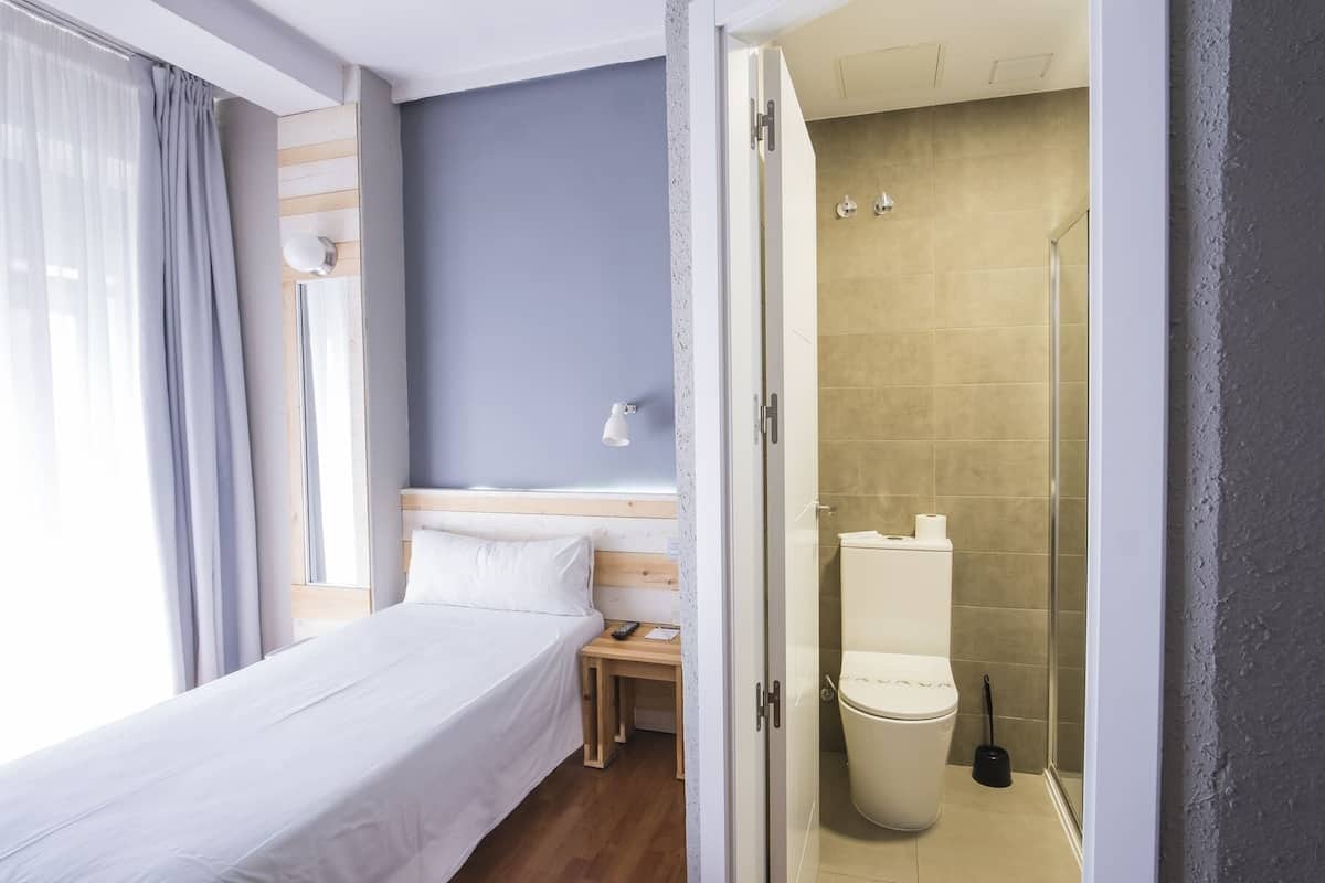 Ein Hotelzimmer mit Bett, Nachttisch und Duschbereich.