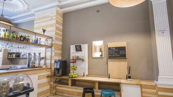 Zona de bar con paneles de madera, una barra con taburetes, una máquina de café y un menú en la pizarra.