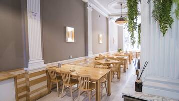 Un restaurant amb taules i cadires de fusta, una barra de marbre i plantes penjants.