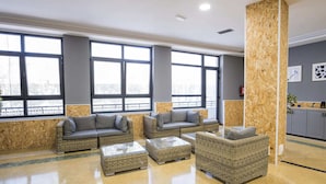 Un área de estar moderna con mobiliario de mimbre, ventanas amplias y vistas a la ciudad.