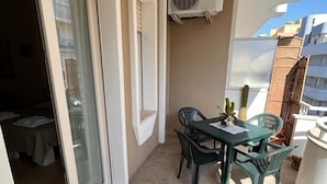 A balcony with a table and chairs, an air conditioning unit, and a view of buildings. - B&B Kalypso (Gallipoli)
