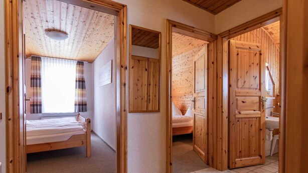Een houten chalet met een bed, een kleine badkamer en een raam met gordijnen.