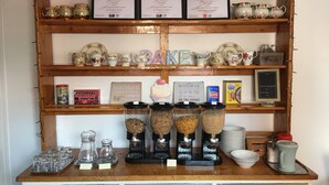 Une étagère en bois sur laquelle sont disposés divers objets de cuisine, notamment des théières, des tasses et des bocaux.