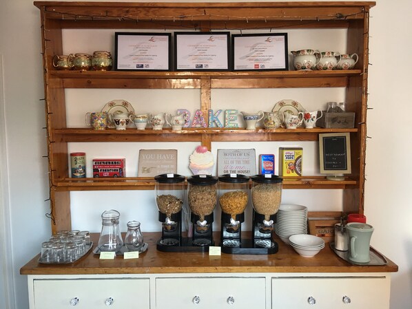 A wooden shelf with various kitchen items, including teapots, cups, and jars.