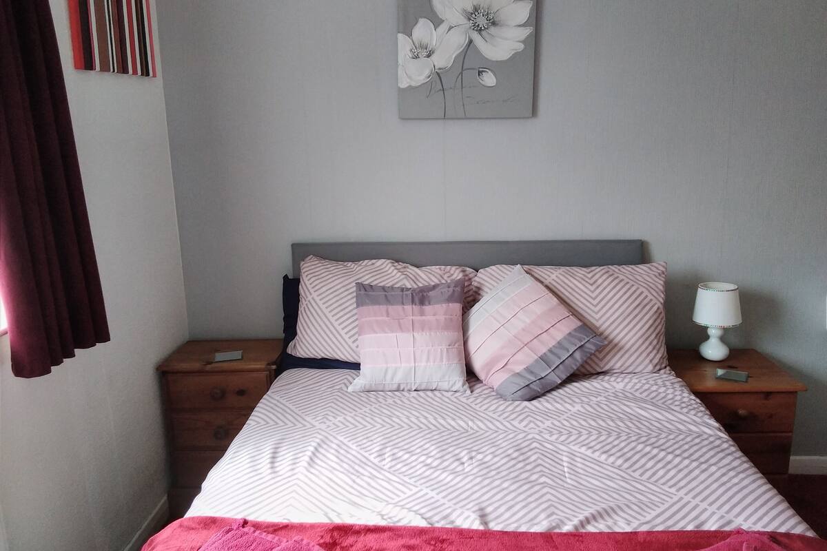 A neatly made bed with patterned bedding, a bedside lamp, and a wall art piece above it.