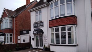 Un bâtiment blanc avec une enseigne indiquant « Whiteways Hotel », ainsi qu’une autre enseigne indiquant « chambre et petit-déjeuner ».