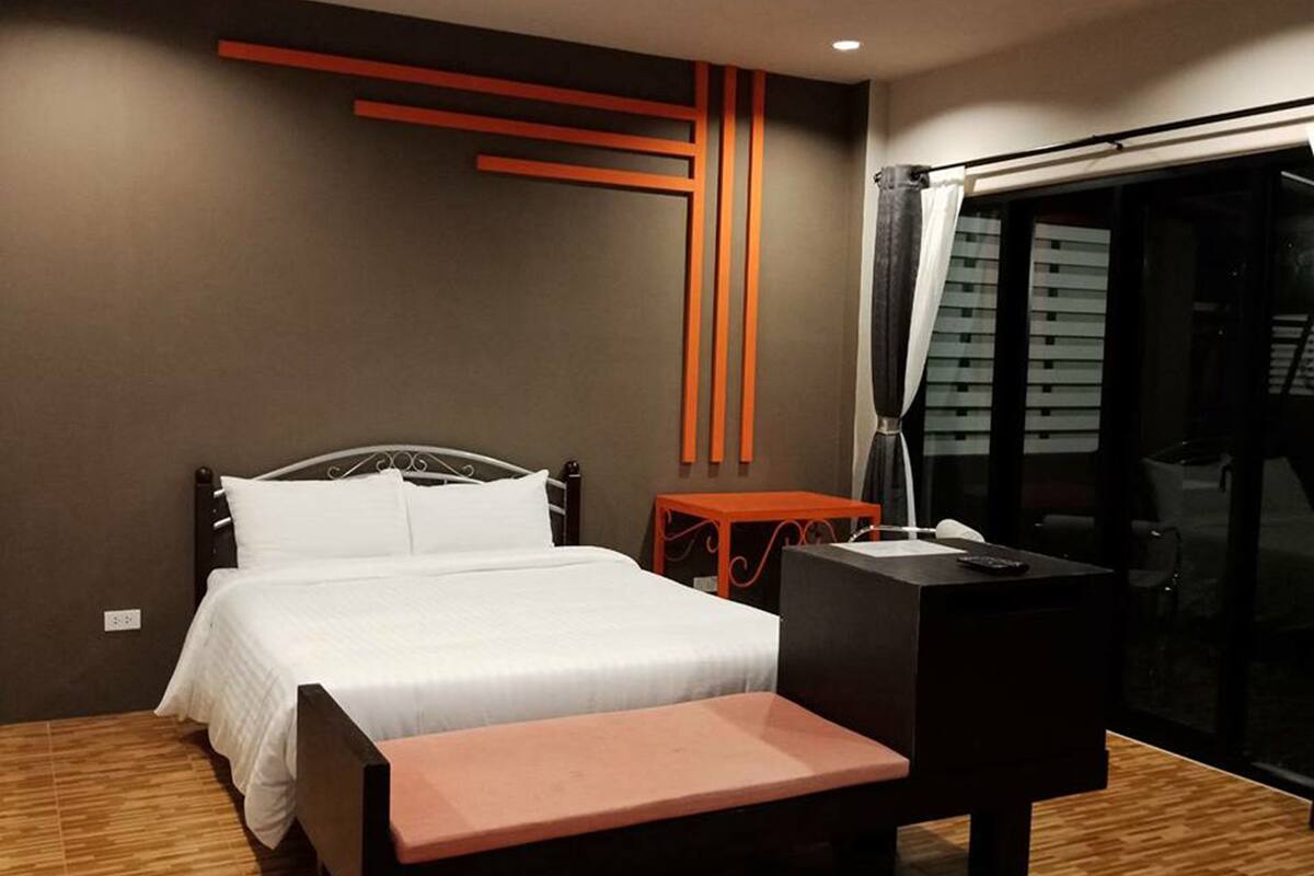 A modern hotel room with a bed, a desk, and a bench.
