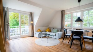 A modern living room with a sofa, coffee table, and dining area. - Apartment 10 (ID 291), Germany (Sankt Peter-Ording)