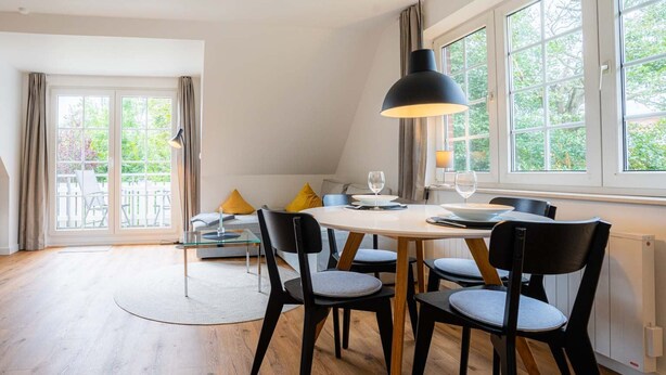 A dining area with a round table, four chairs, and a large window with curtains. - Apartment 10 (ID 291), Germany (Sankt Peter-Ording)