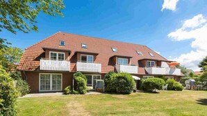 A two-story house with a red-tiled roof, white balconies, and a well-maintained lawn. - Apartment 10 (ID 291), Germany (Sankt Peter-Ording)