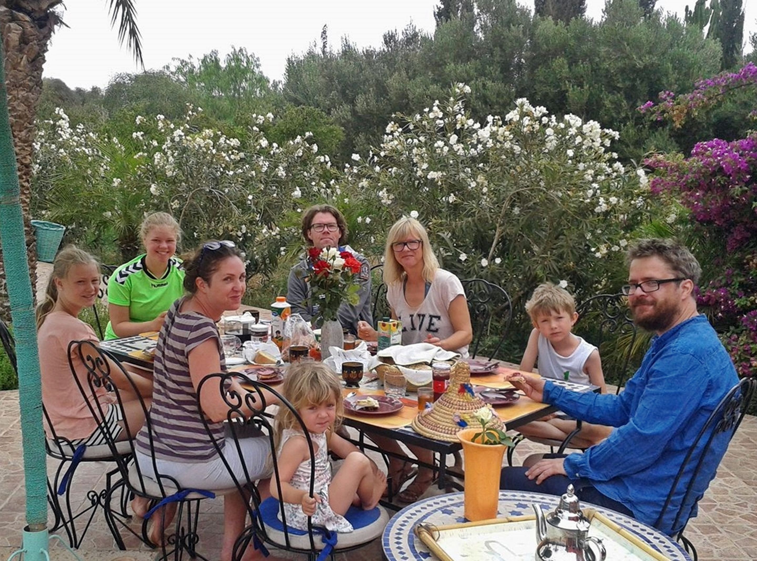 Een groep mensen zit rond een tafel met diverse gerechten en drankjes.