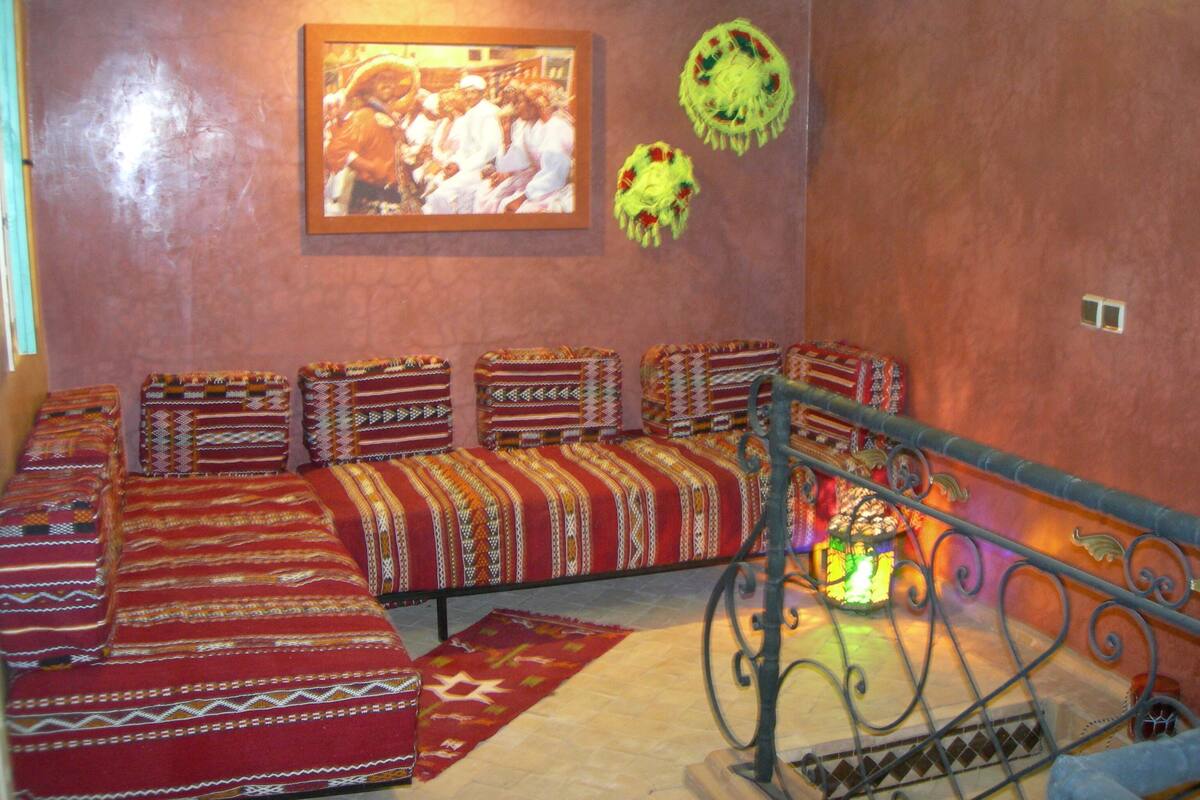 A room with a sofa set against a red wall, a framed picture, and a decorative lantern.