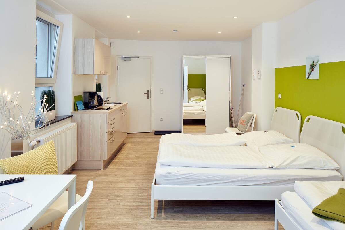 A modern hotel room with a bed, bedside table, and a desk area with a chair.
