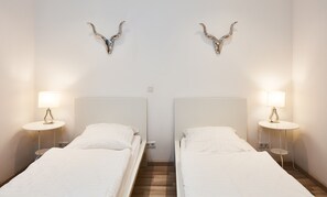 Una habitación de hotel con dos camas individuales, cada una con una mesita de noche y lámpara.