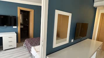 A bedroom with a bed, a dresser, a TV, and a mirror.